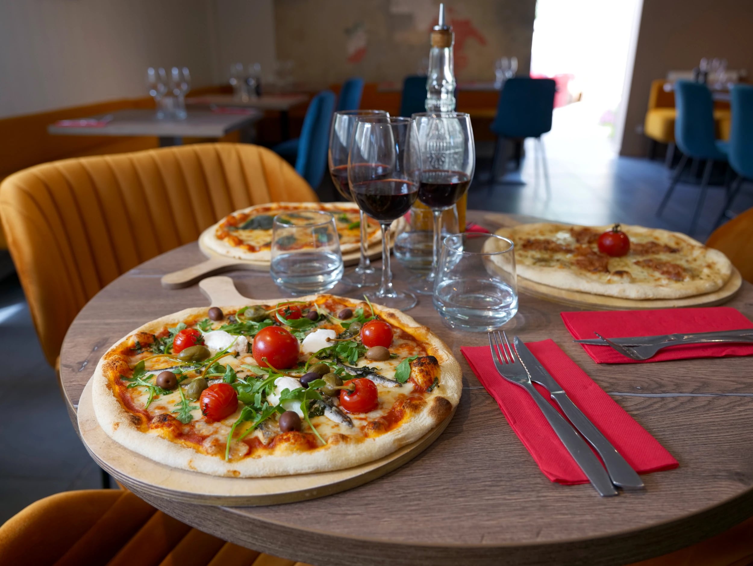 Salle du restaurant O'Divino Melesse, pizzas et verres de vin sur la table